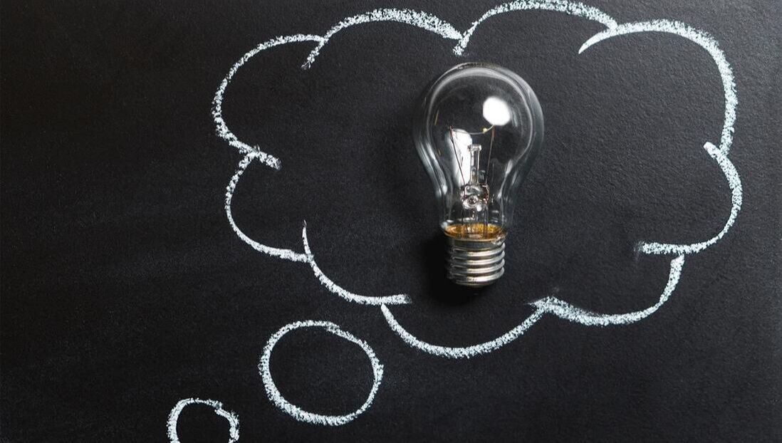 A light bulb is in a thought bubble drawn on a blackboard.