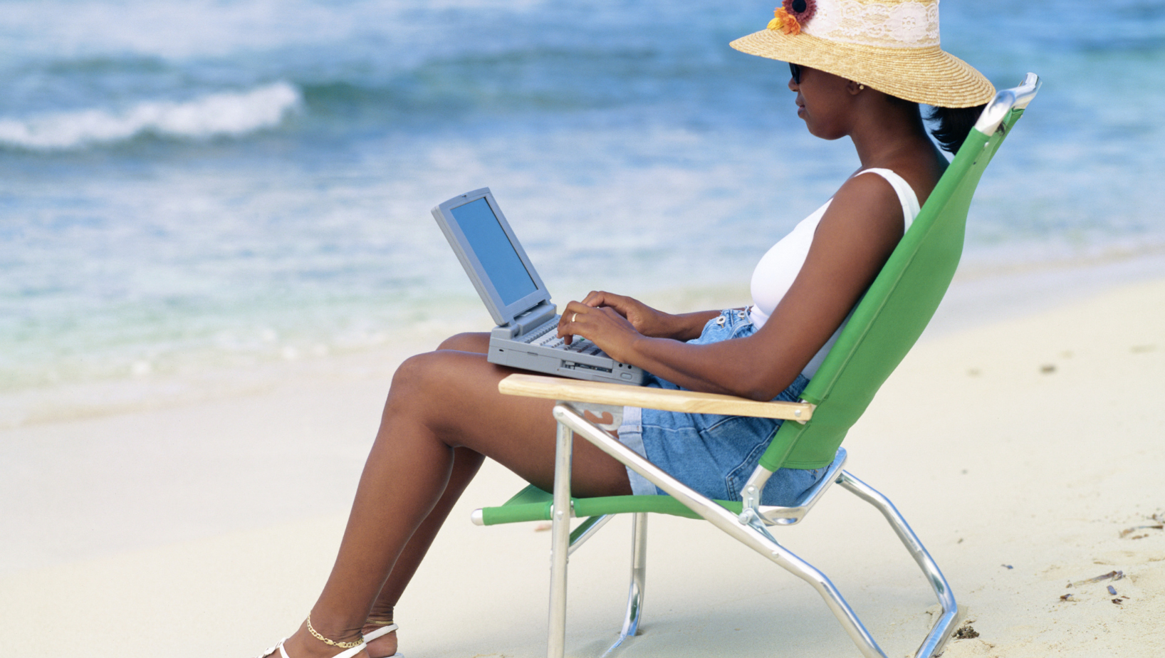 Virtual Assistant or small business owner checks email from a laptop at the beach | Freedom Makers