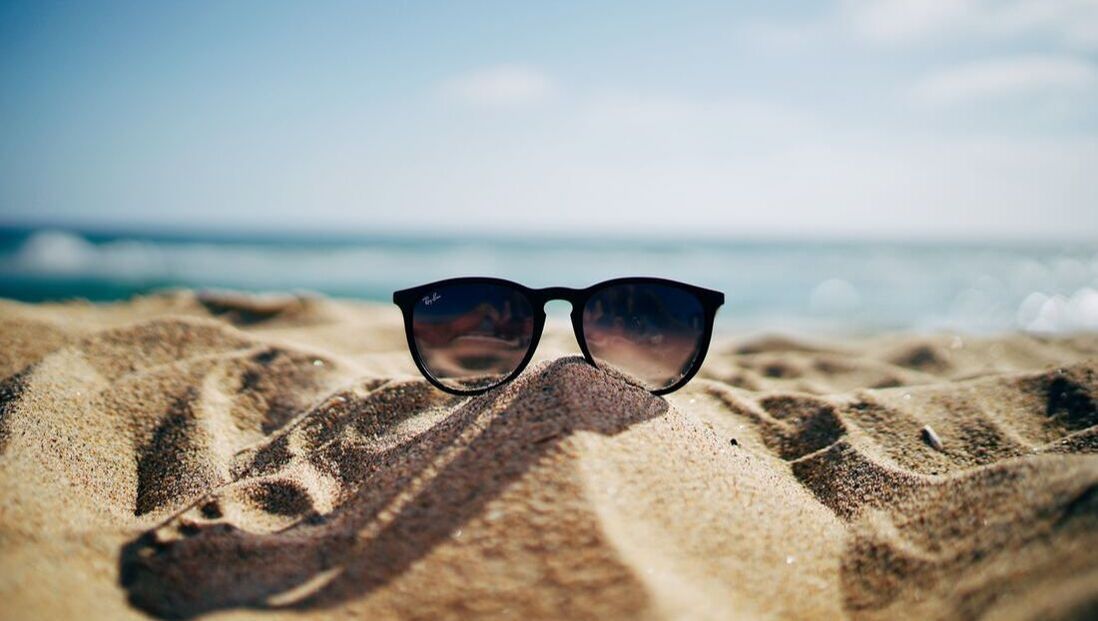 A pair of sunglasses sitting on top of a pile of sand on a beach.