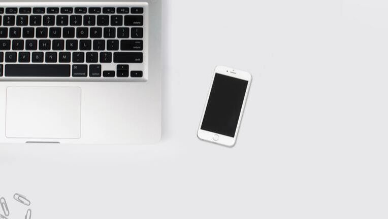 A laptop and a cell phone are on a white table.