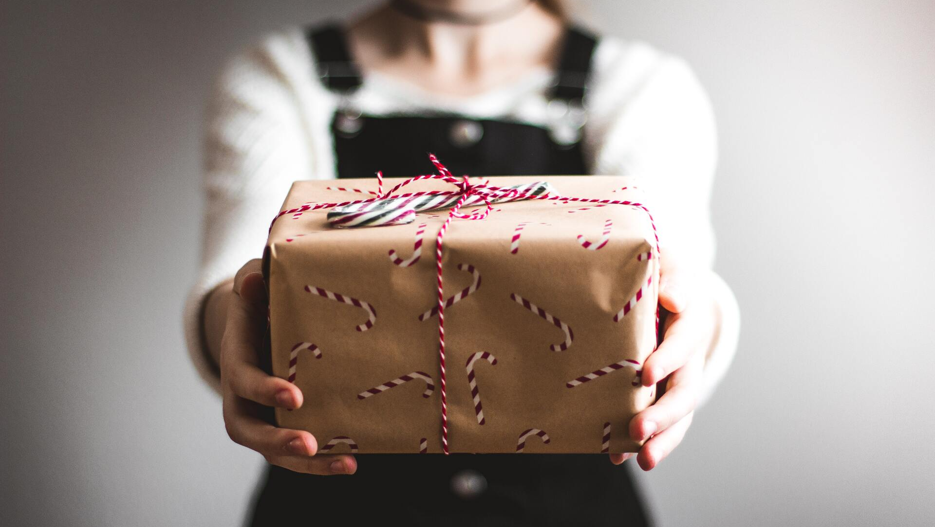 A woman is holding a wrapped gift in her hands.