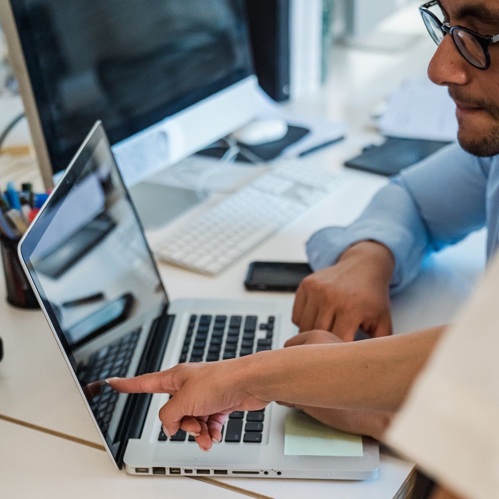 Man points to a laptop screen and delegates tasks.