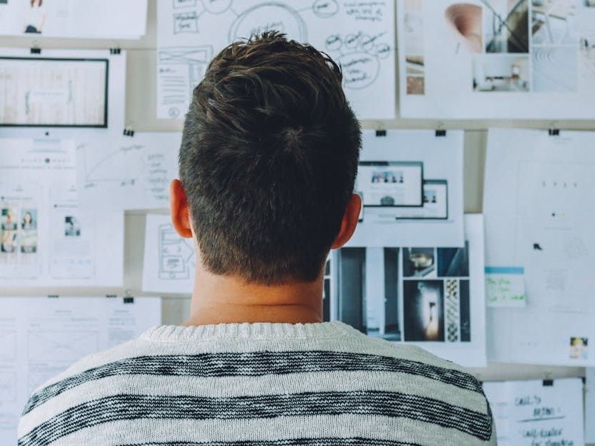 A man looks at plans pinned to a bulletin board.