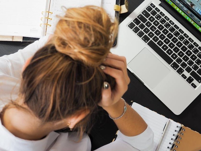 A woman has her head bent over a keyboard.