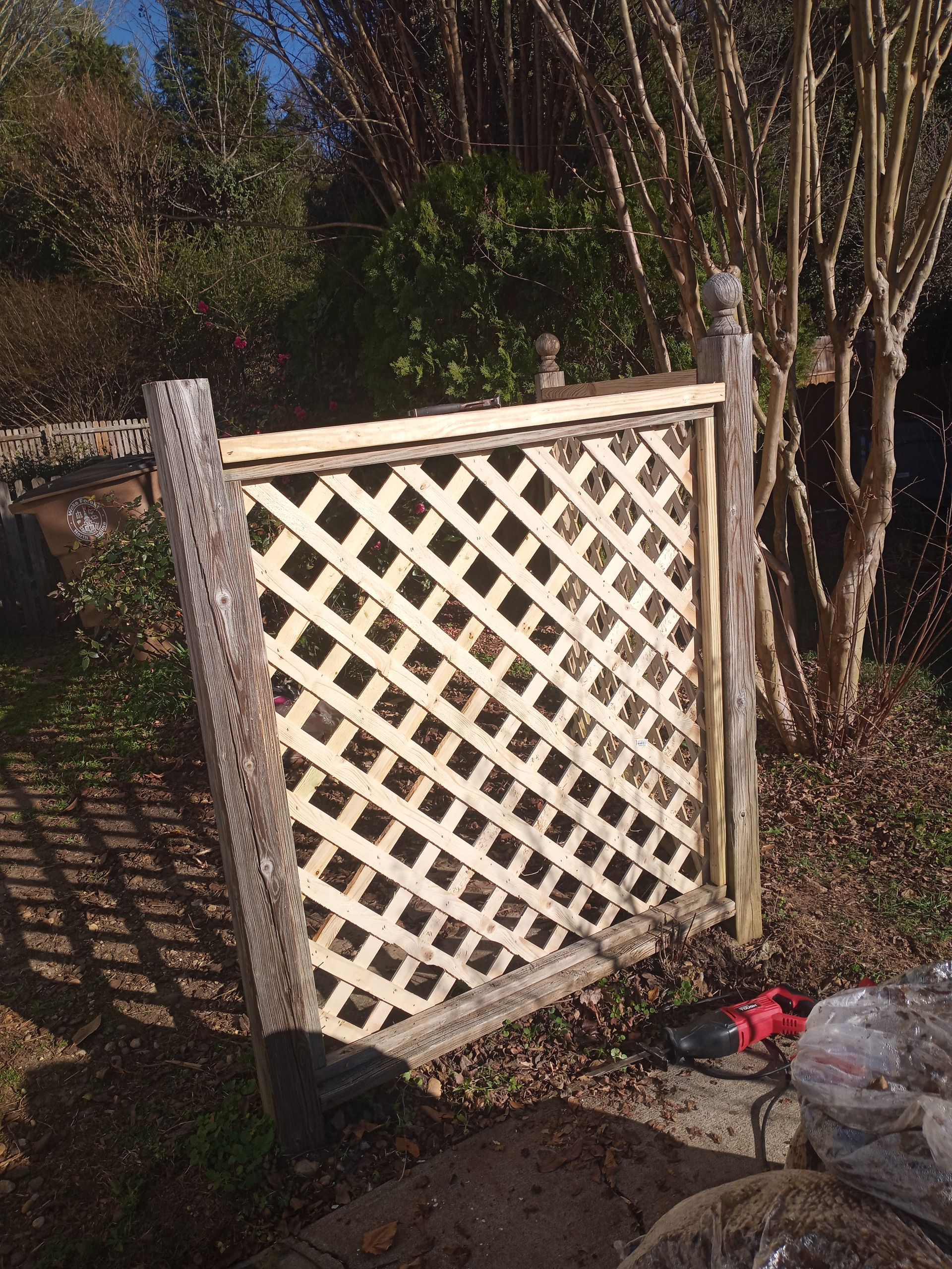 A wooden lattice fence is sitting in the middle of a garden.