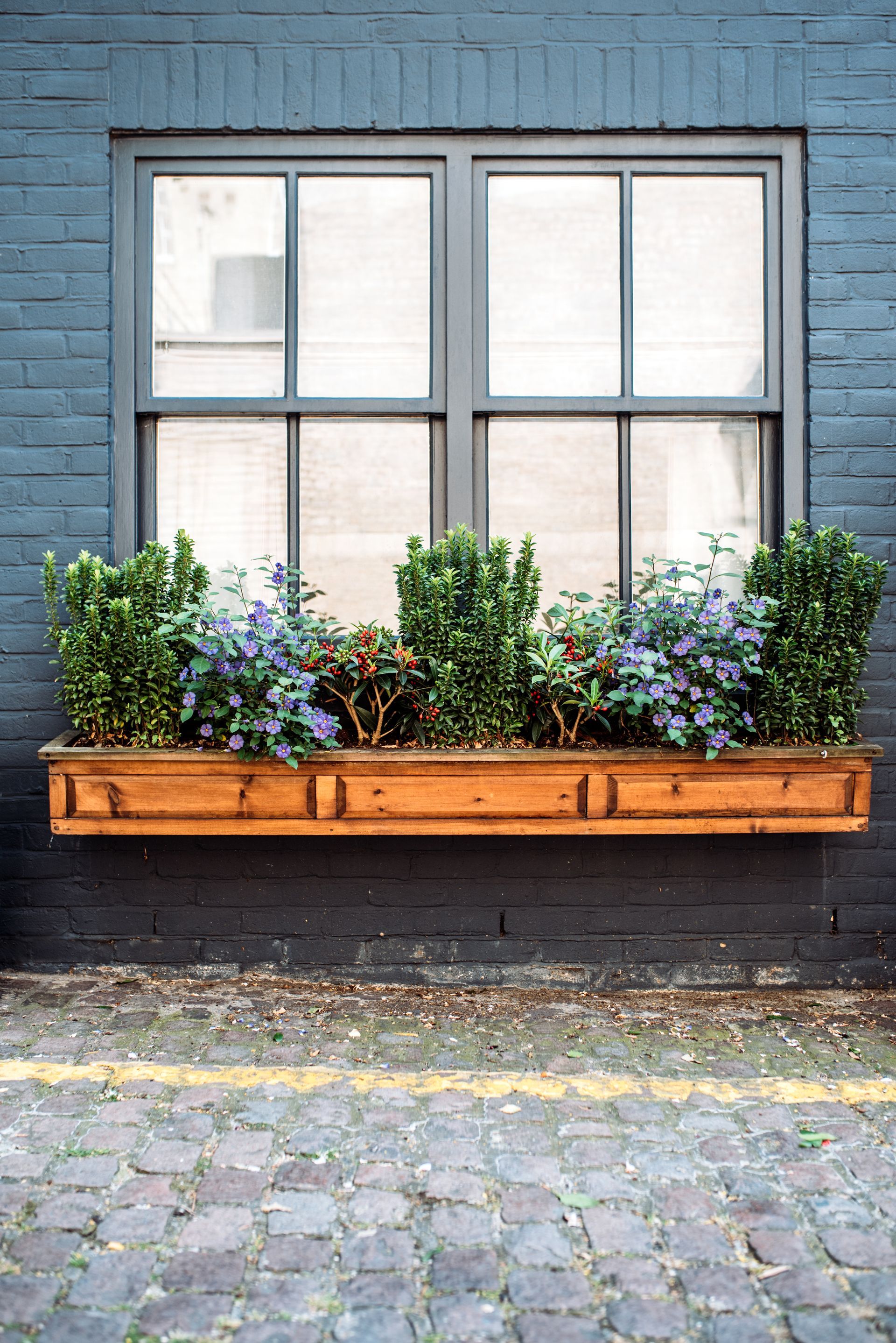 A window box with flowers in it is hanging on a brick wall.