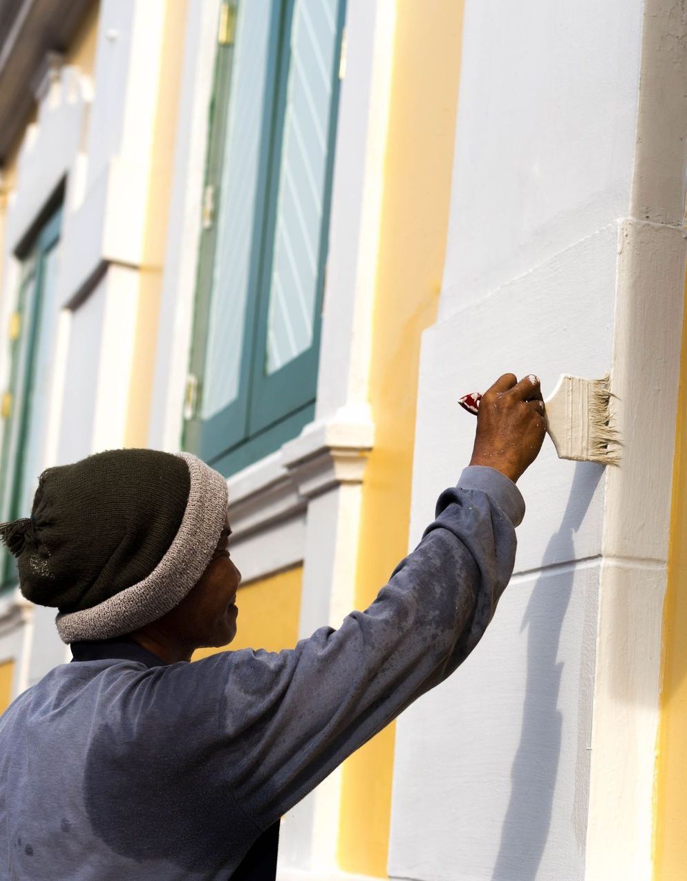 A man is painting the side of a building with a brush