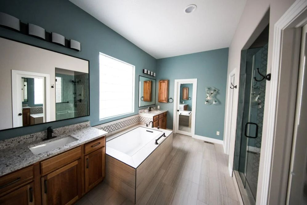A bathroom with a bathtub , sinks , mirrors and a walk in shower.