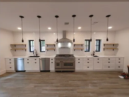 Modern white kitchen with stainless steel appliances, black accents, and exposed shelving.