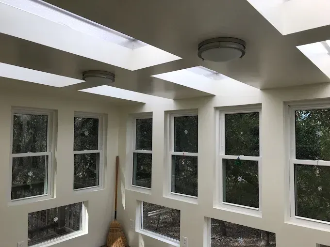 Interior room with multiple windows and skylights, painted white with circular lights.