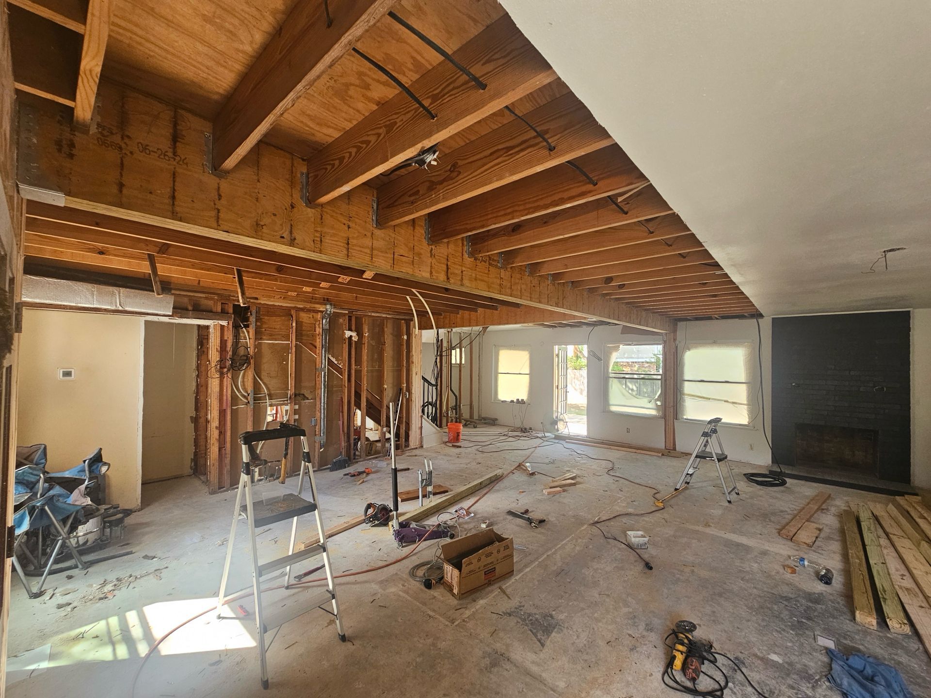 Interior room undergoing renovation, exposed beams, walls in progress, tools and materials scattered.
