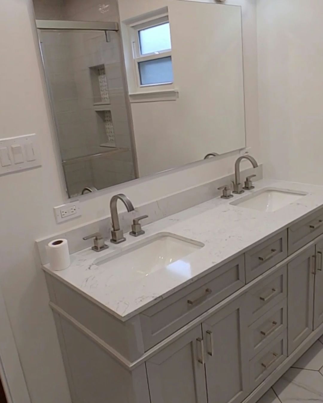 White double vanity with quartz countertop, two sinks, and brushed nickel faucets in a bathroom.