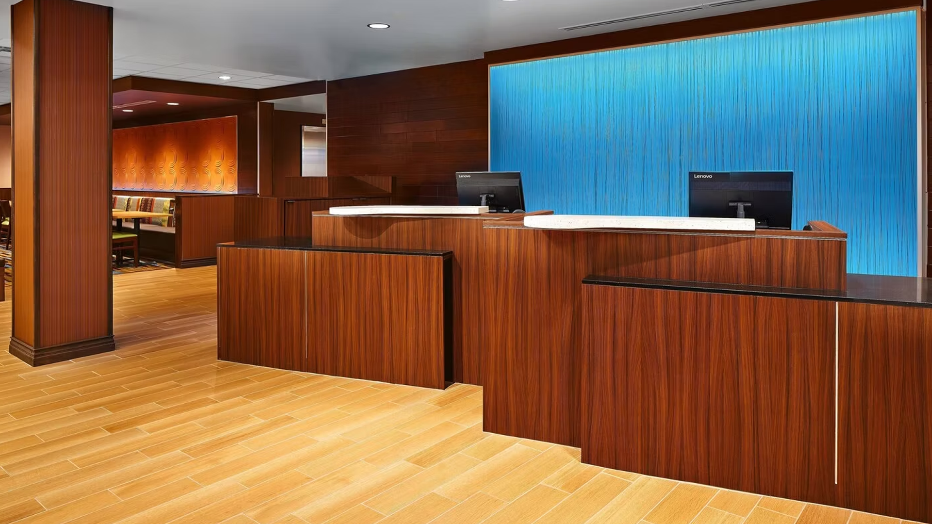 Reception desk with wooden panels, light wood floor, and blue illuminated wall.
