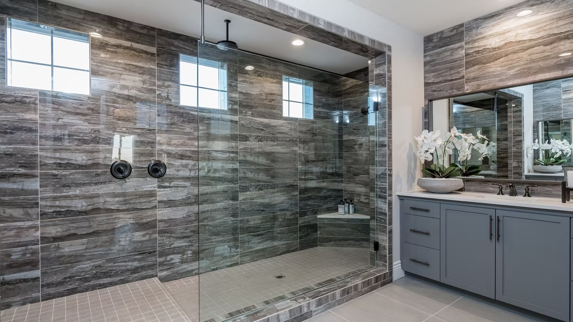 Modern bathroom with gray and brown patterned tile shower and vanity.
