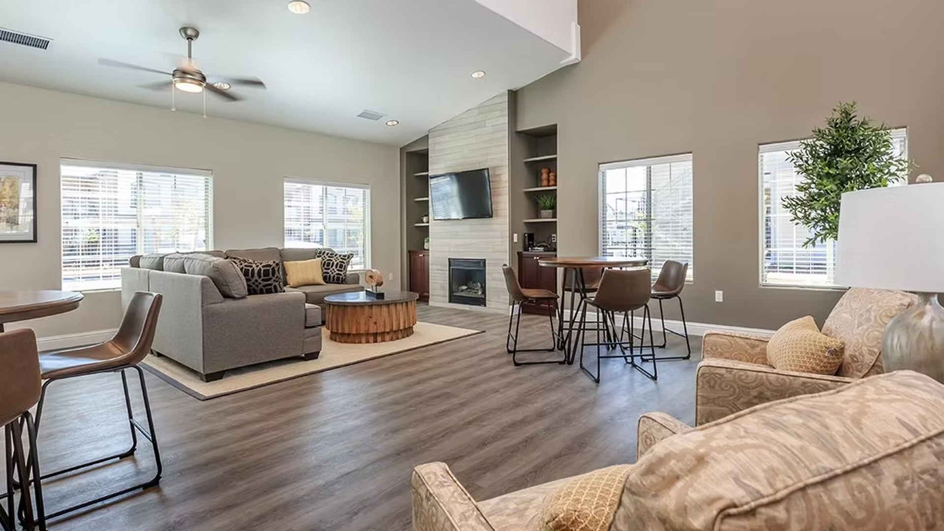 Spacious living room with gray sofa, fireplace, dining area, and large windows.