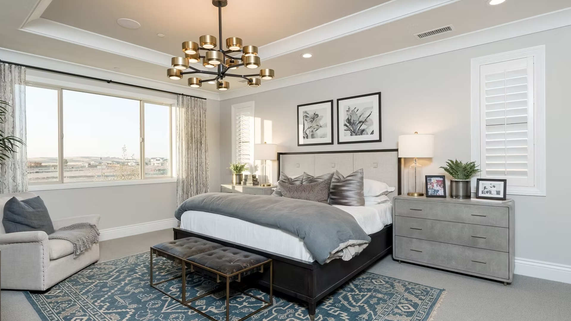 Bedroom with large windows, gray walls, bed, rug, and chandelier.