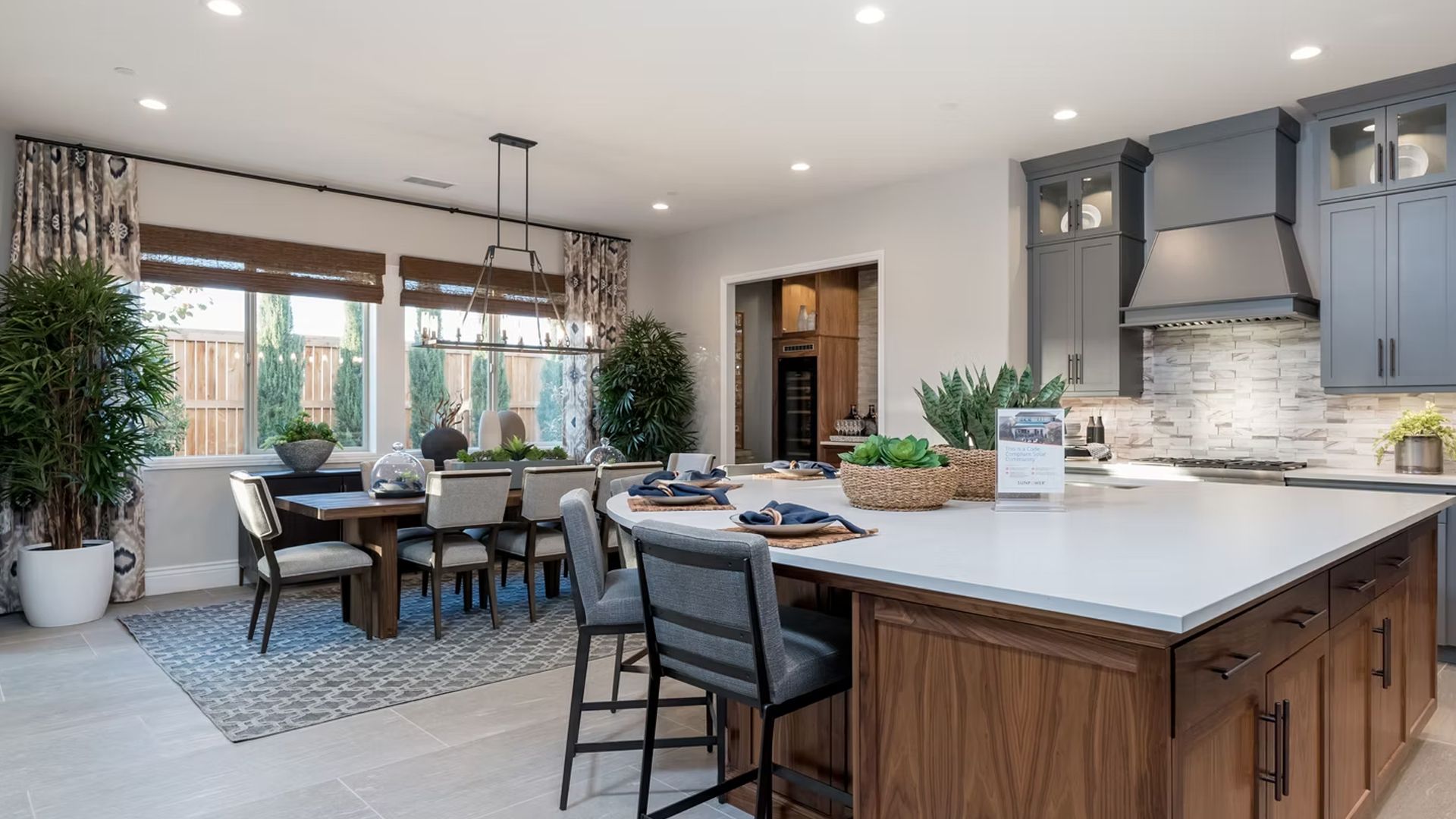 Kitchen and dining room with island, dark wood cabinets, gray upper cabinets, and a dining table.