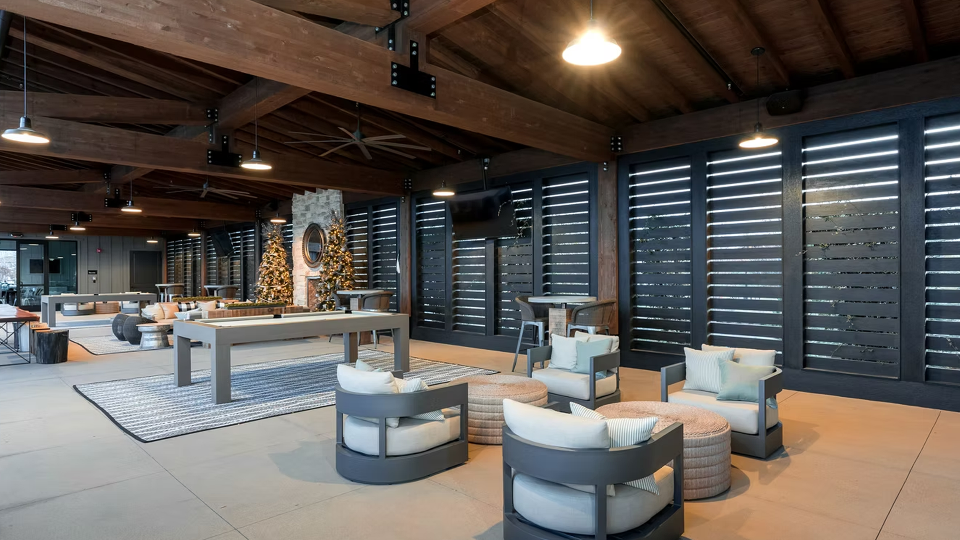 Lounge area with gray seating, slatted windows, wooden beams, and a Christmas tree.