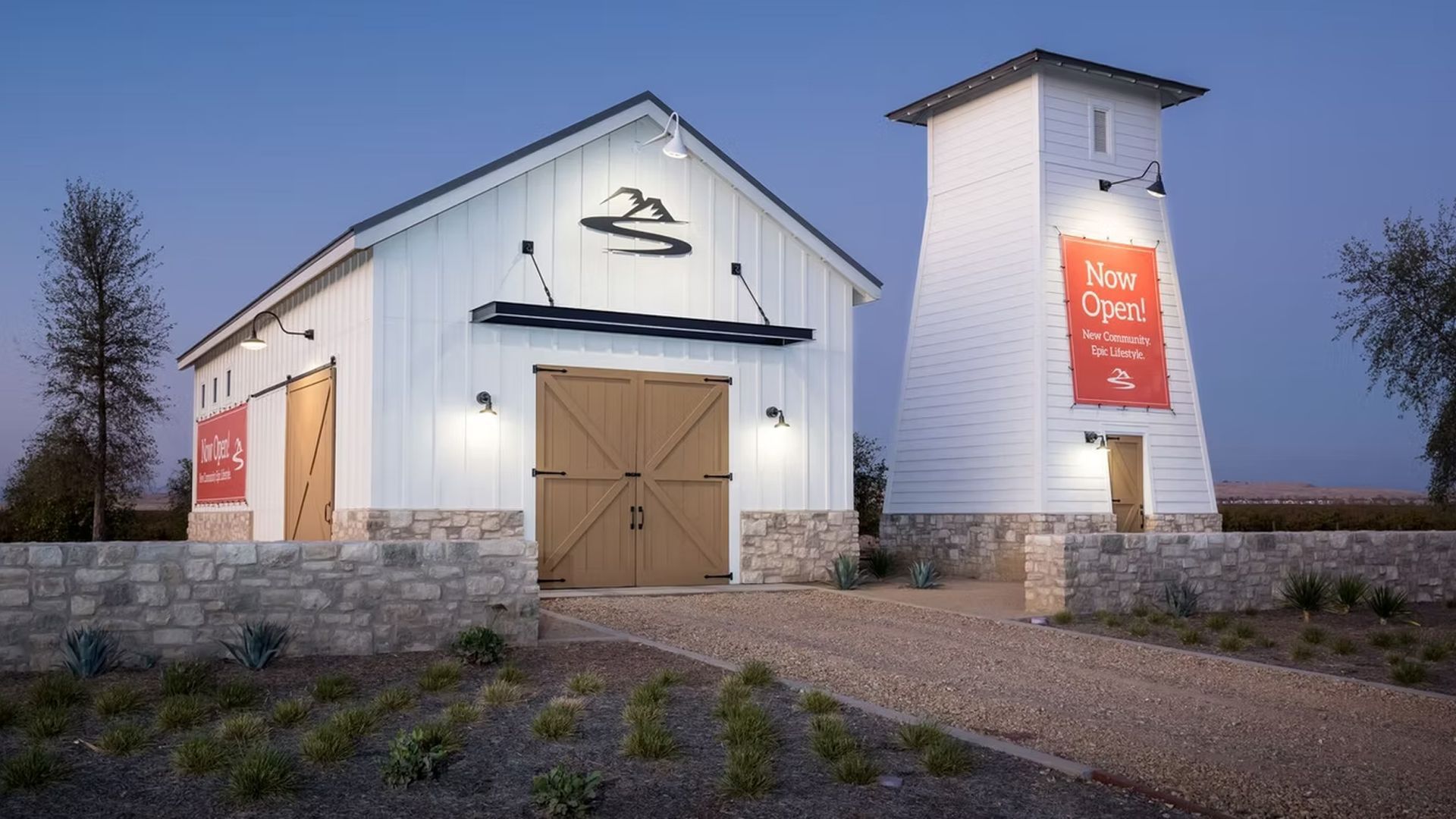 White barn and tower with wooden doors, a gravel driveway, and a 