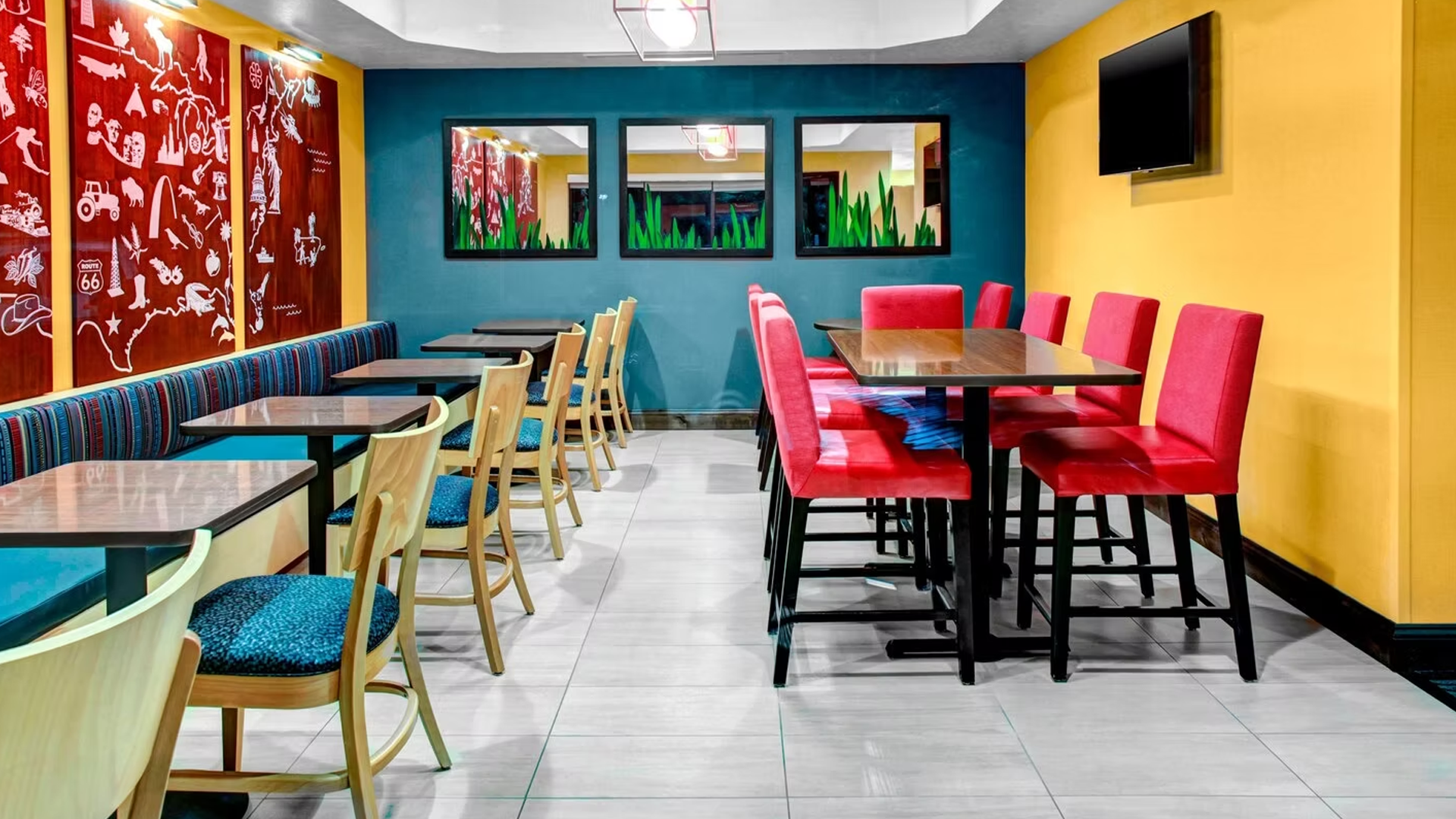 Restaurant dining area with blue, red, and yellow accents. Tables, chairs, and wall art visible.
