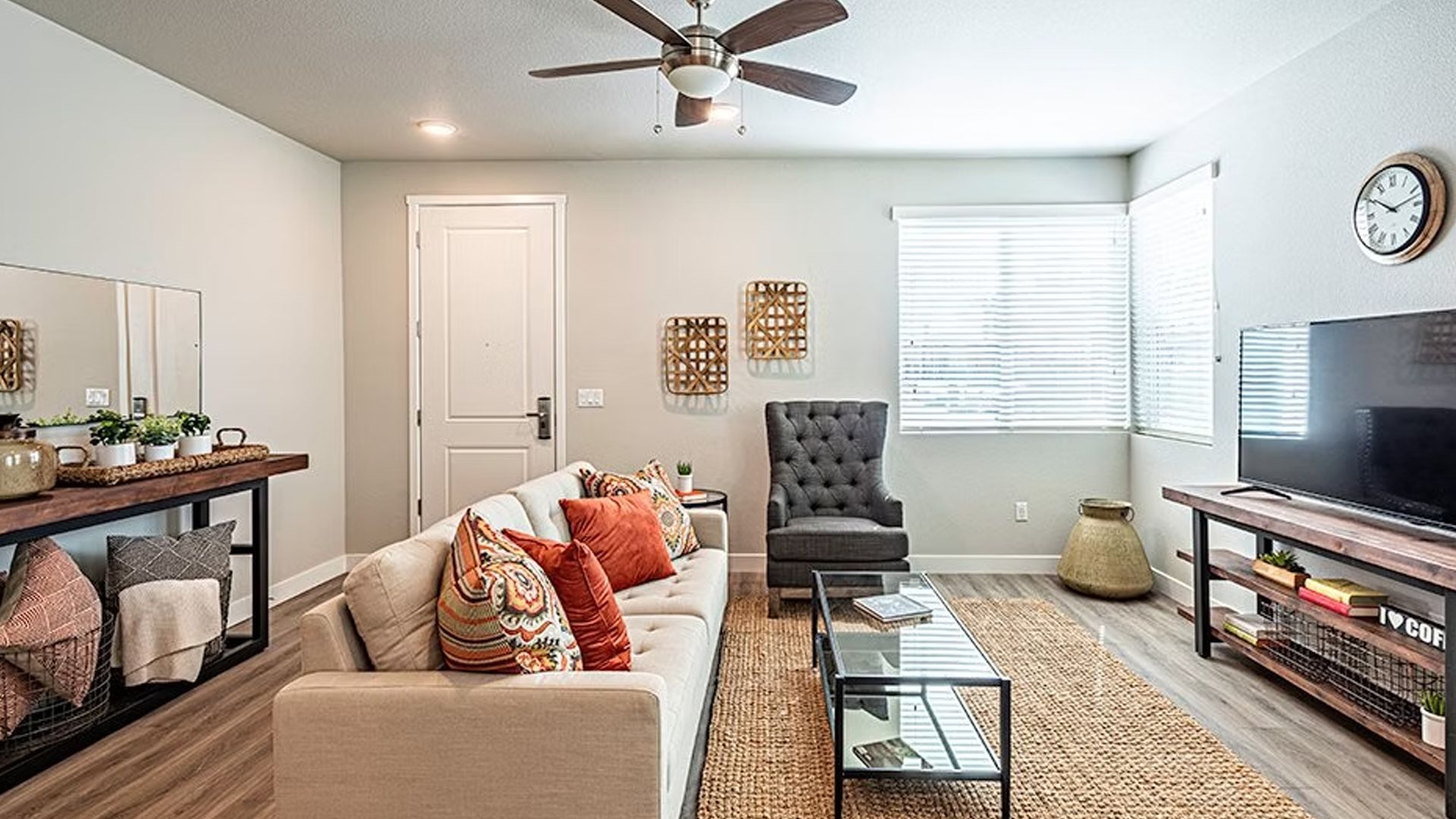 Living room with neutral tones: couch, armchair, TV, rug, and decorative accents.