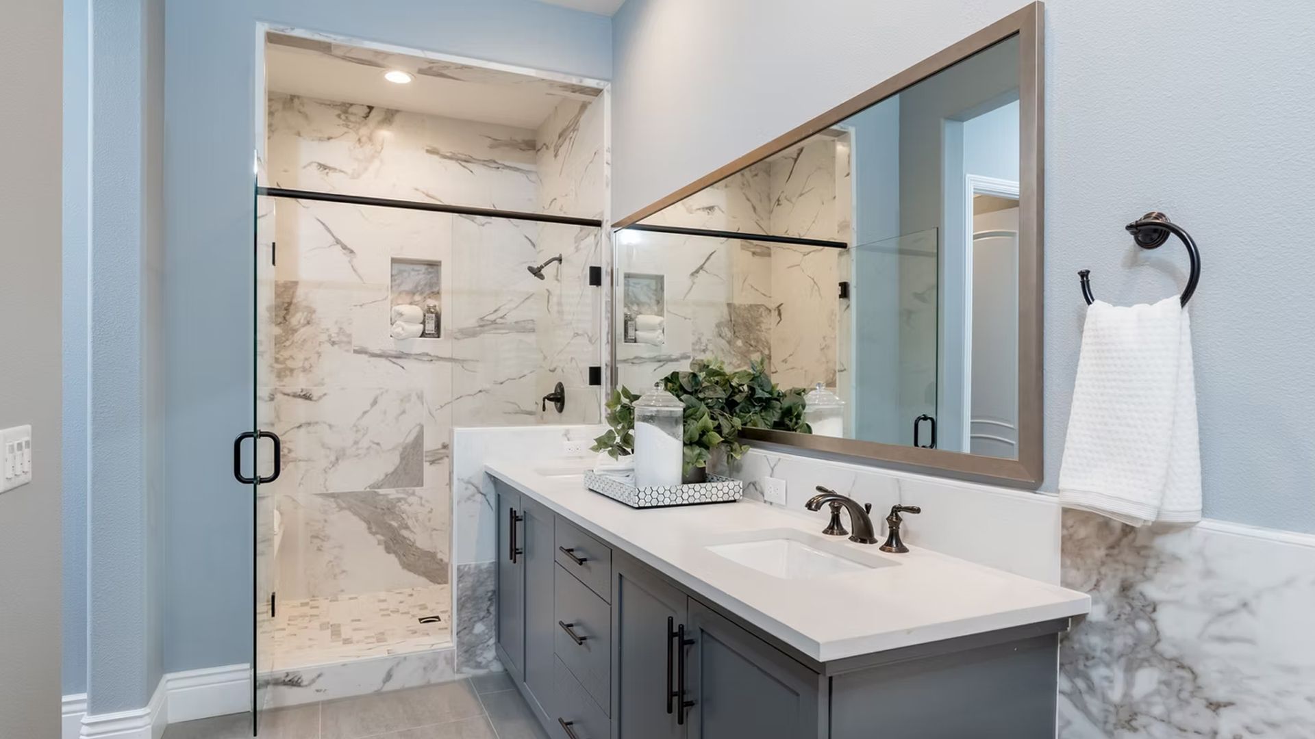 Modern bathroom with blue walls, a marble shower, and a gray vanity.