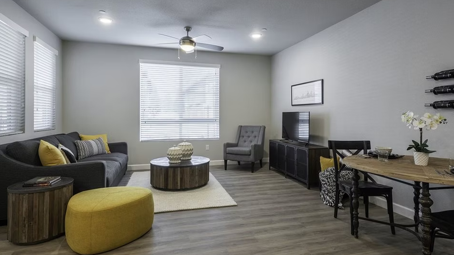 Living room with gray sofa, yellow accents, and dining table.
