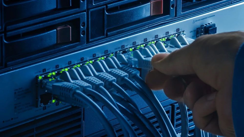 Hand Plugging a Network Cable Into a Server, Ports Lit Green — Superior Wifi in Lismore, NSW