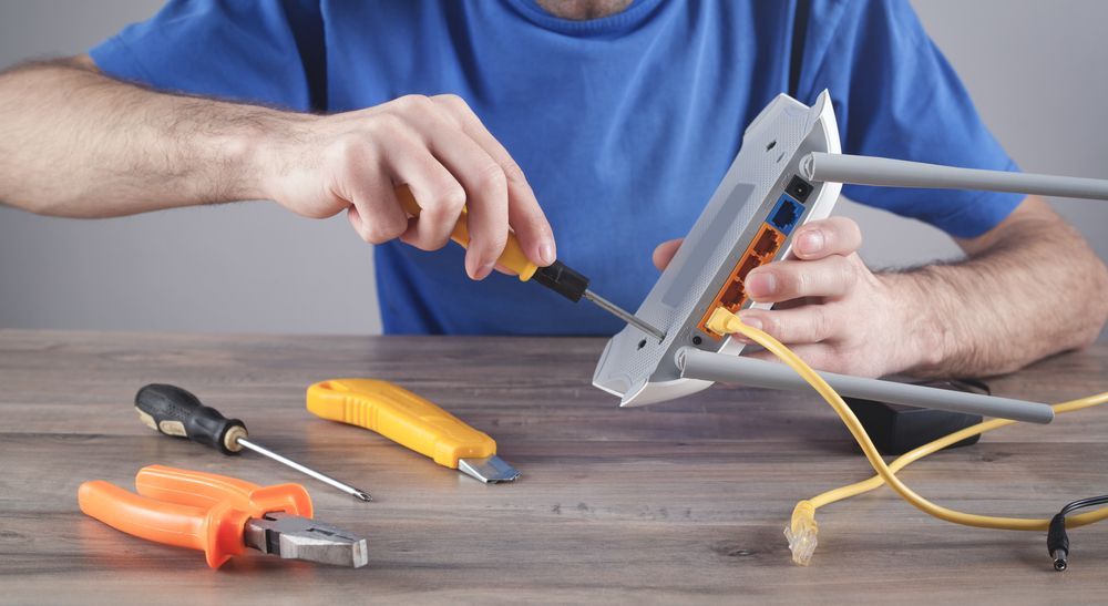 Person Using Screwdriver On Router With Yellow Cables — Superior Wifi in East Ballina, NSW