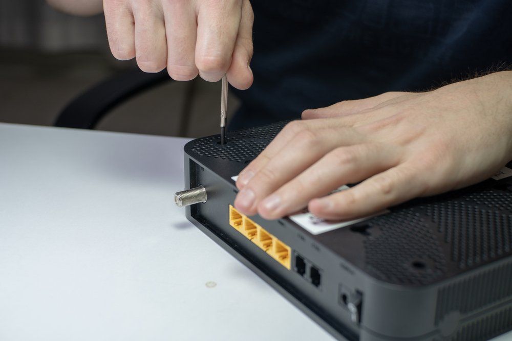 Person Using Screwdriver To Open Black Device With Yellow Ports — Superior Wifi in East Ballina, NSW