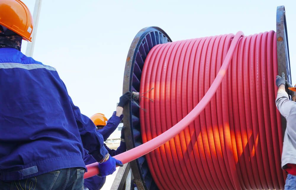 Worker Pulling High Voltage Cable Line — Electrician in Orange
