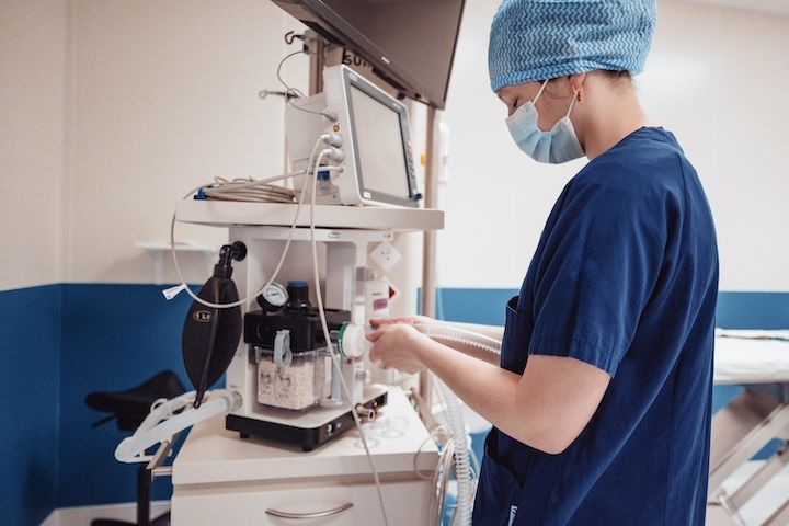 Un chirurgien portant un masque et une blouse travaille sur une machine dans une salle d'opération.