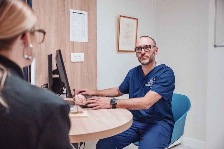 Un médecin est assis à une table et parle à un patient.