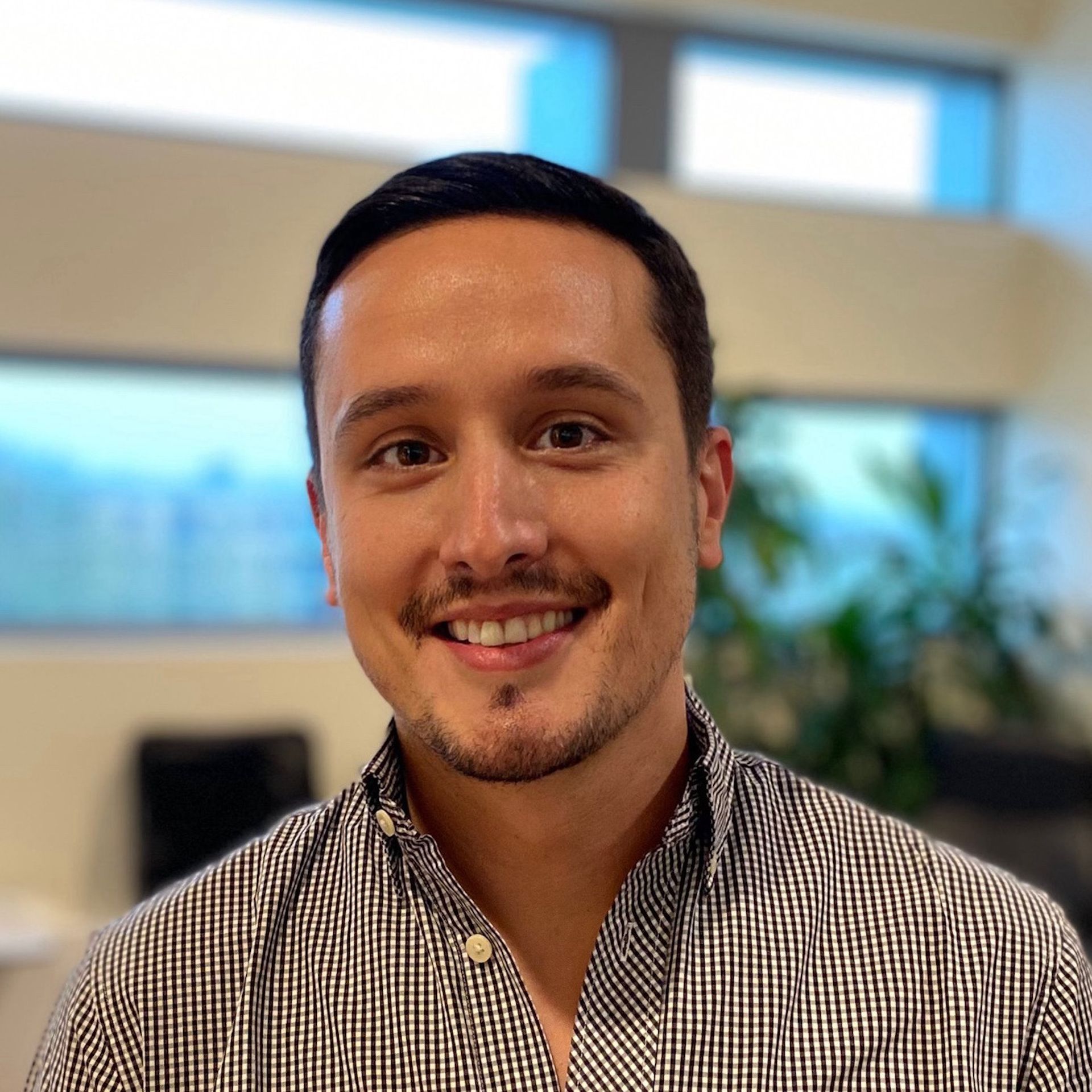 Un homme en chemise à carreaux sourit à la caméra