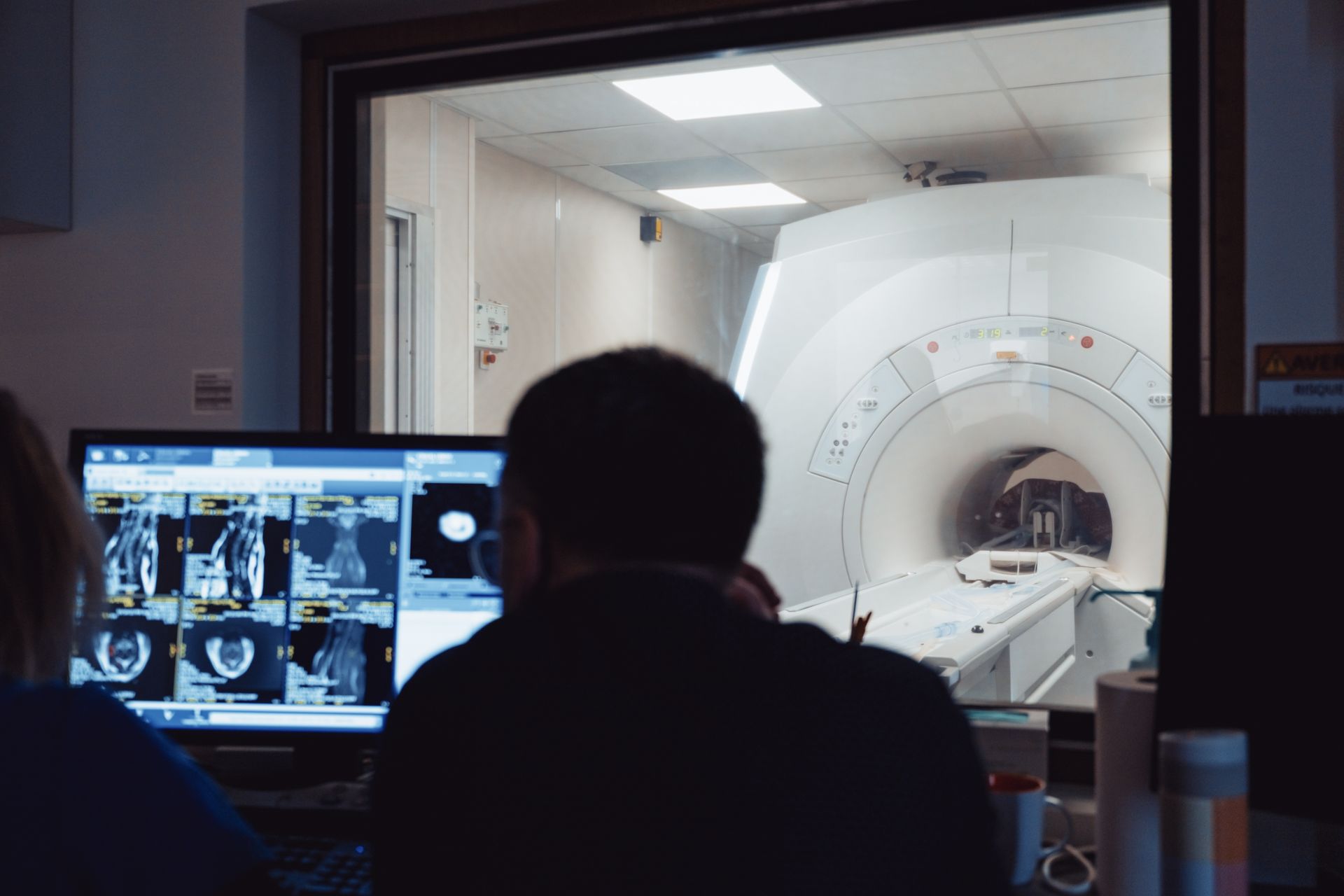 Un homme regarde un écran d'ordinateur devant une machine IRM.