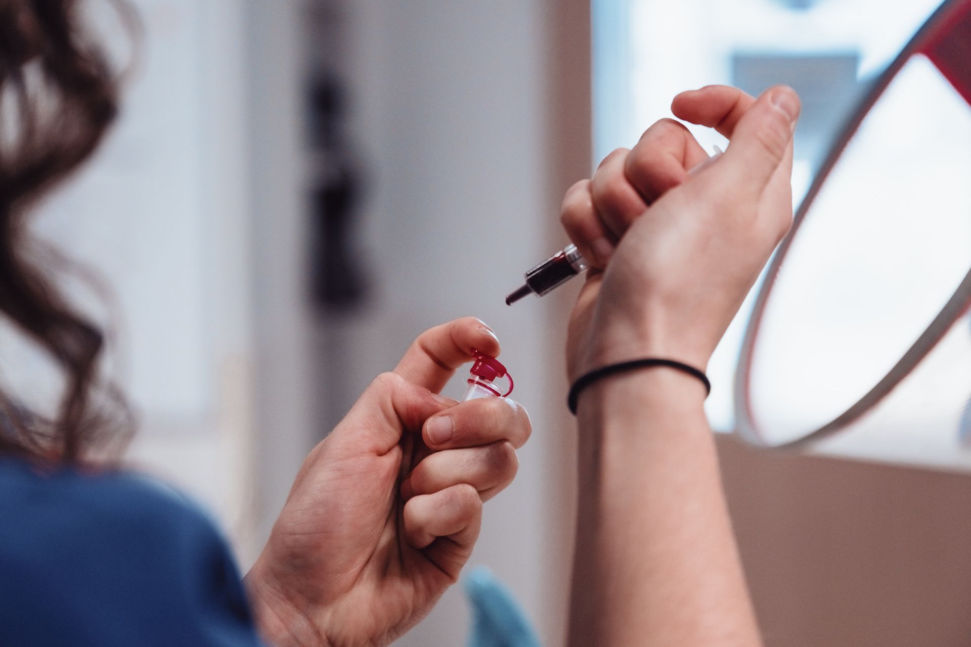 Une femme tient une bouteille de liquide rouge dans ses mains.