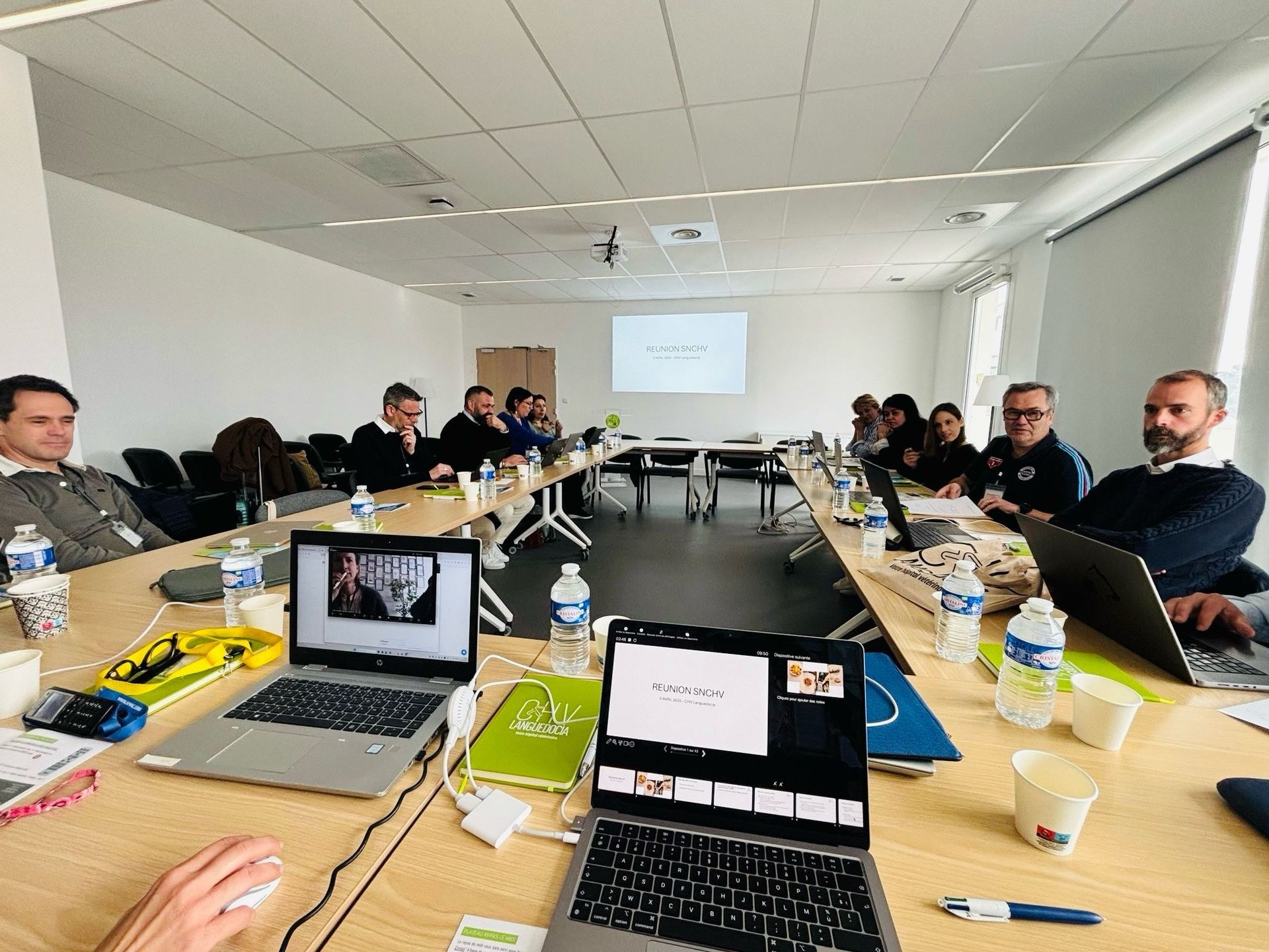 Un groupe de personnes est assis à une longue table avec des ordinateurs portables.