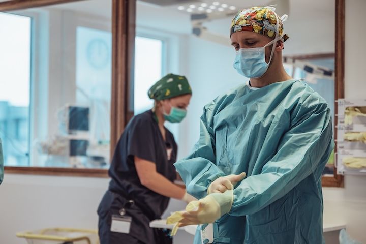 Un chirurgien met ses gants dans une salle d'opération.