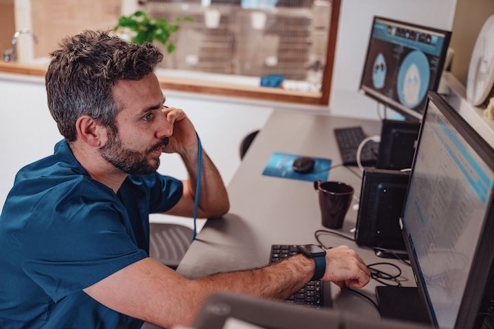 Un homme est assis à un bureau et regarde un écran d'ordinateur.