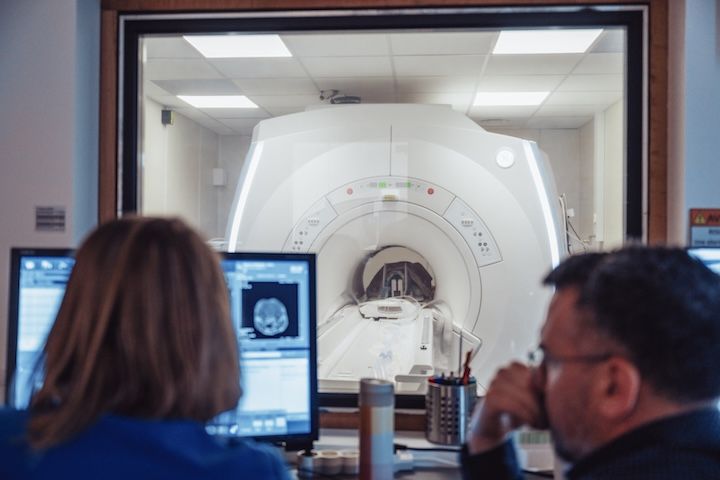 Un homme et une femme sont assis devant une machine IRM.