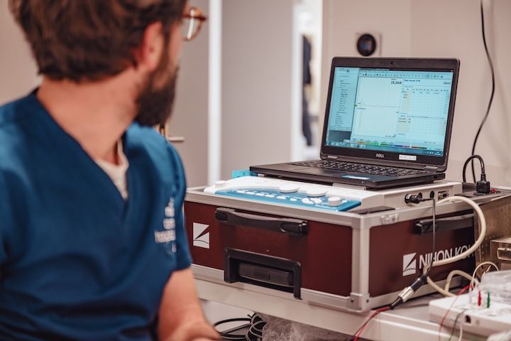 Un homme en blouse bleue est assis devant un ordinateur portable.