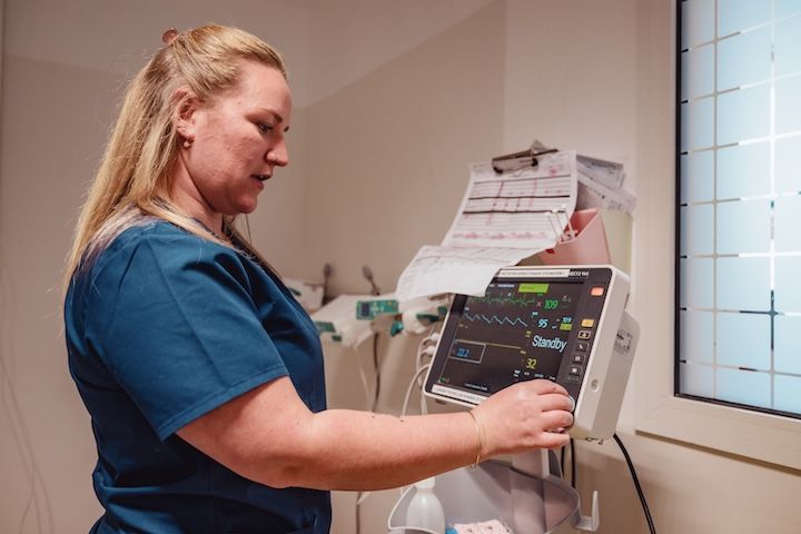 Une infirmière travaille sur un appareil médical dans une chambre d'hôpital.
