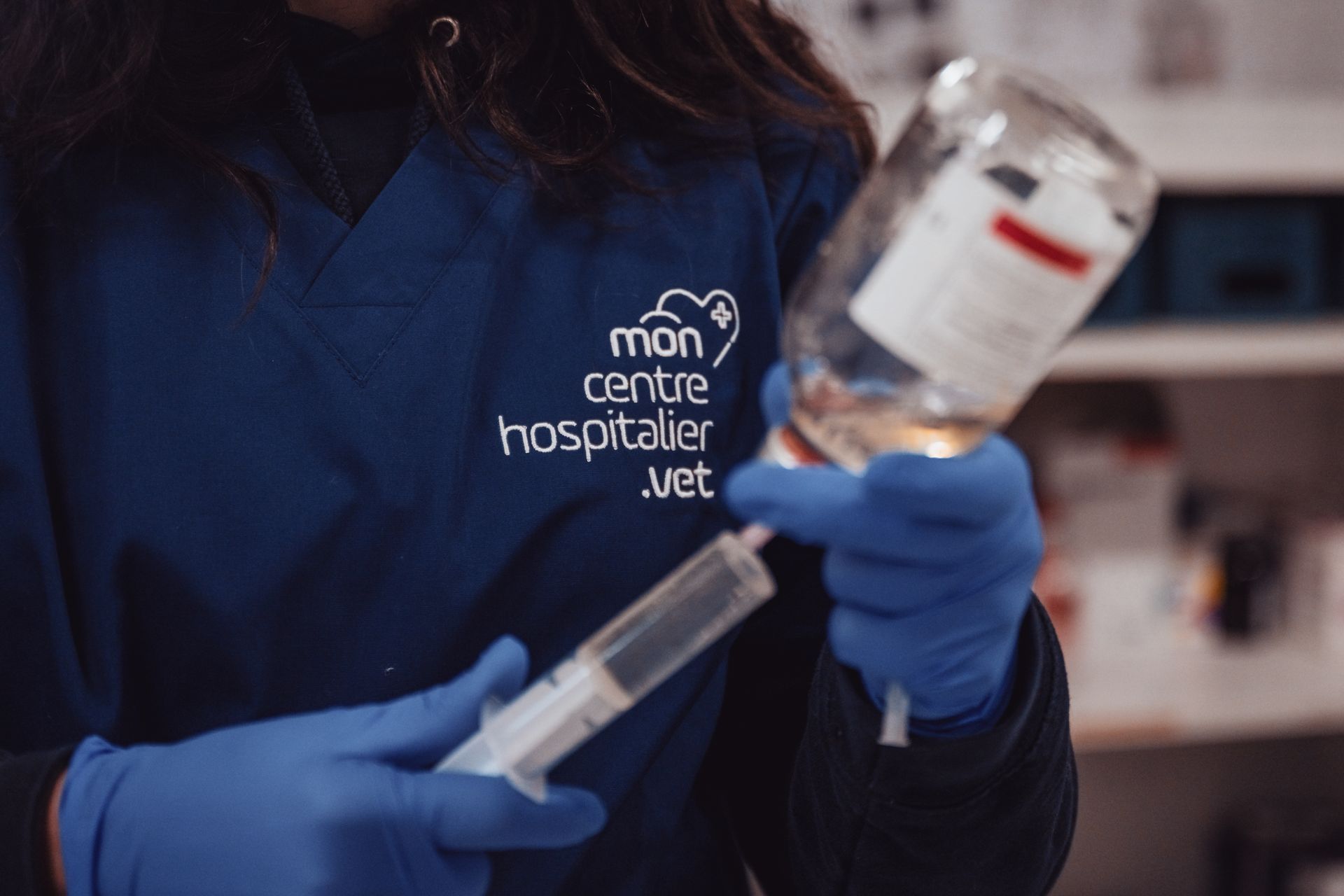 Une femme en uniforme bleu tient une seringue et une bouteille de liquide.