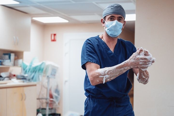 Un chirurgien portant un masque et des gants se lave les mains dans un hôpital.