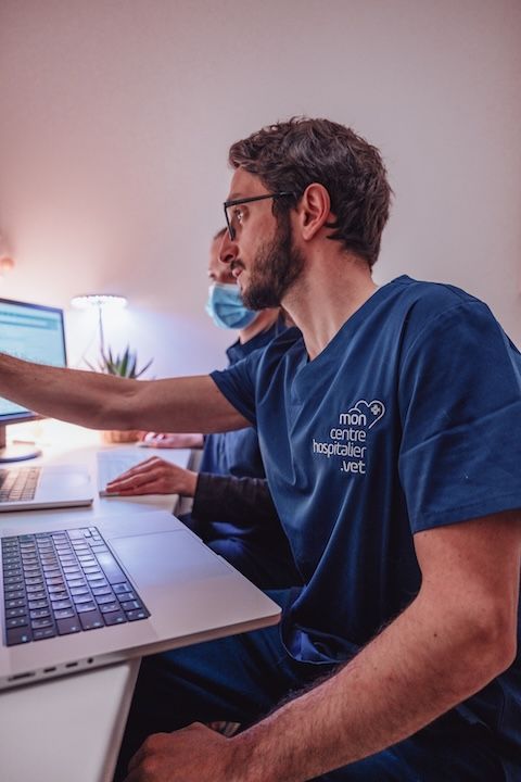 Deux médecins sont assis à un bureau et regardent un ordinateur portable.