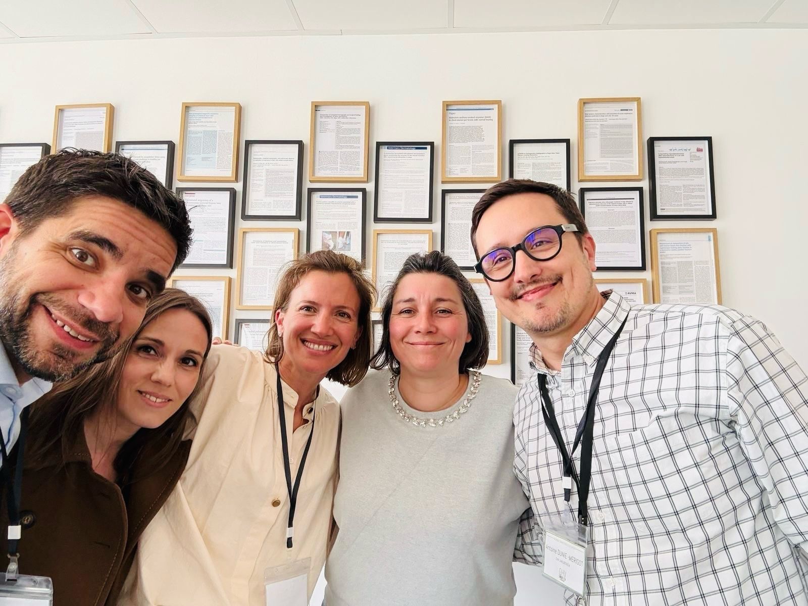 Un groupe de personnes pose pour une photo devant un mur de certificats vétérinaires