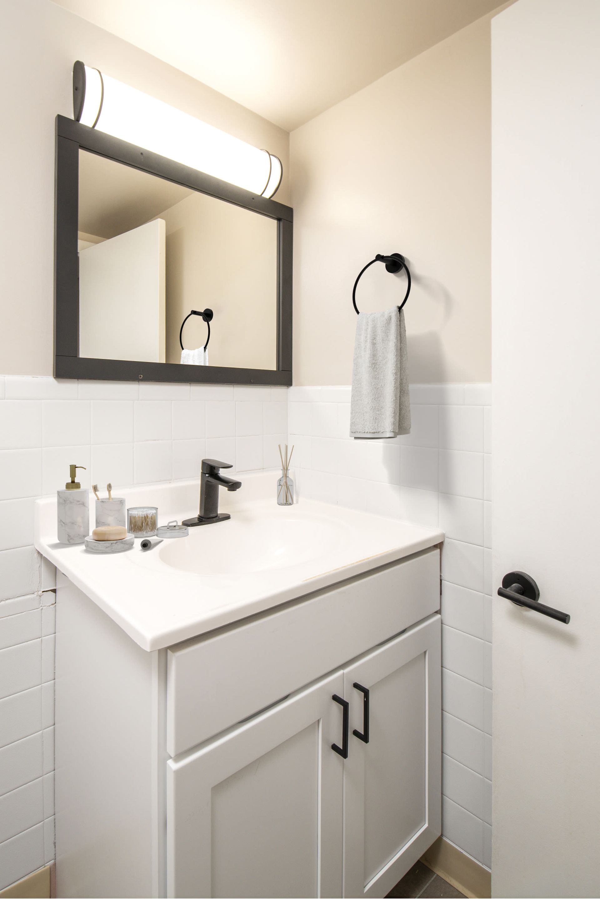 Bathroom vanity with white cabinet, white tiled backsplash, black faucet, and towel ring at Westover Pointe in Wilmington, DE.