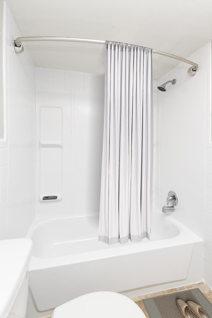 Bright white bathroom with a tub/shower, curved curtain, and tiled walls at Westover Pointe in Wilmington, DE.