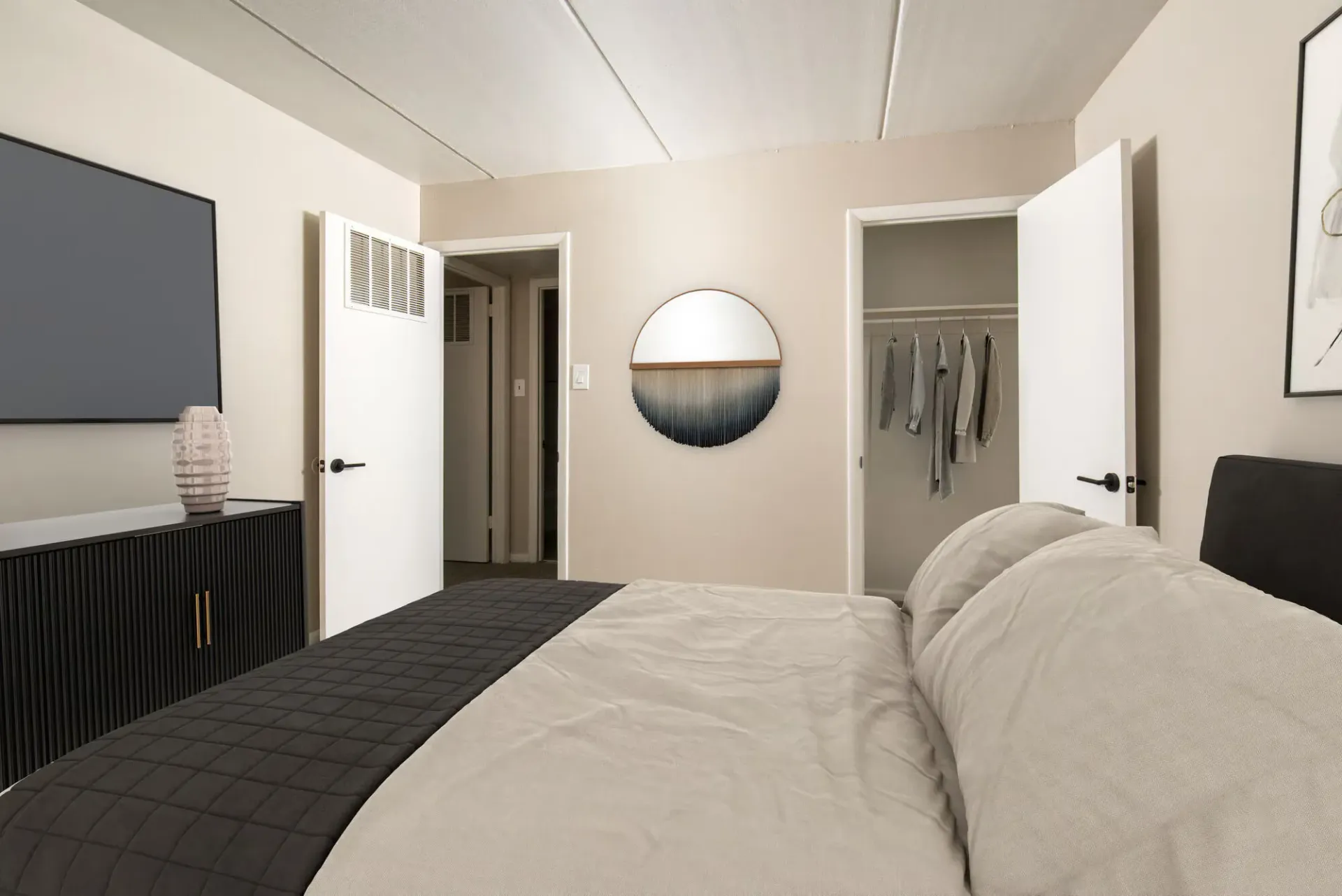 Bedroom in an apartment featuring a bed, dresser, and open closet doors at Westover Pointe in Wilmington, DE.