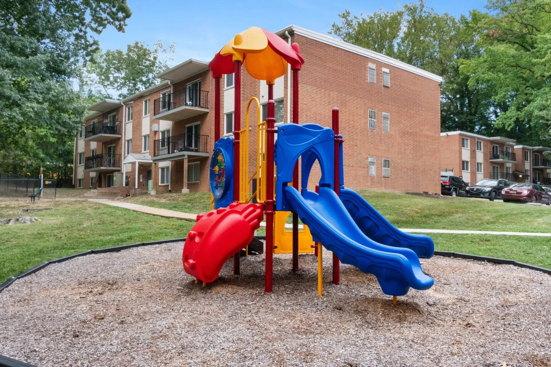 Colorful playground structure with two blue slides in front of a brick apartment building at Westover Pointe in Wilmington, DE.